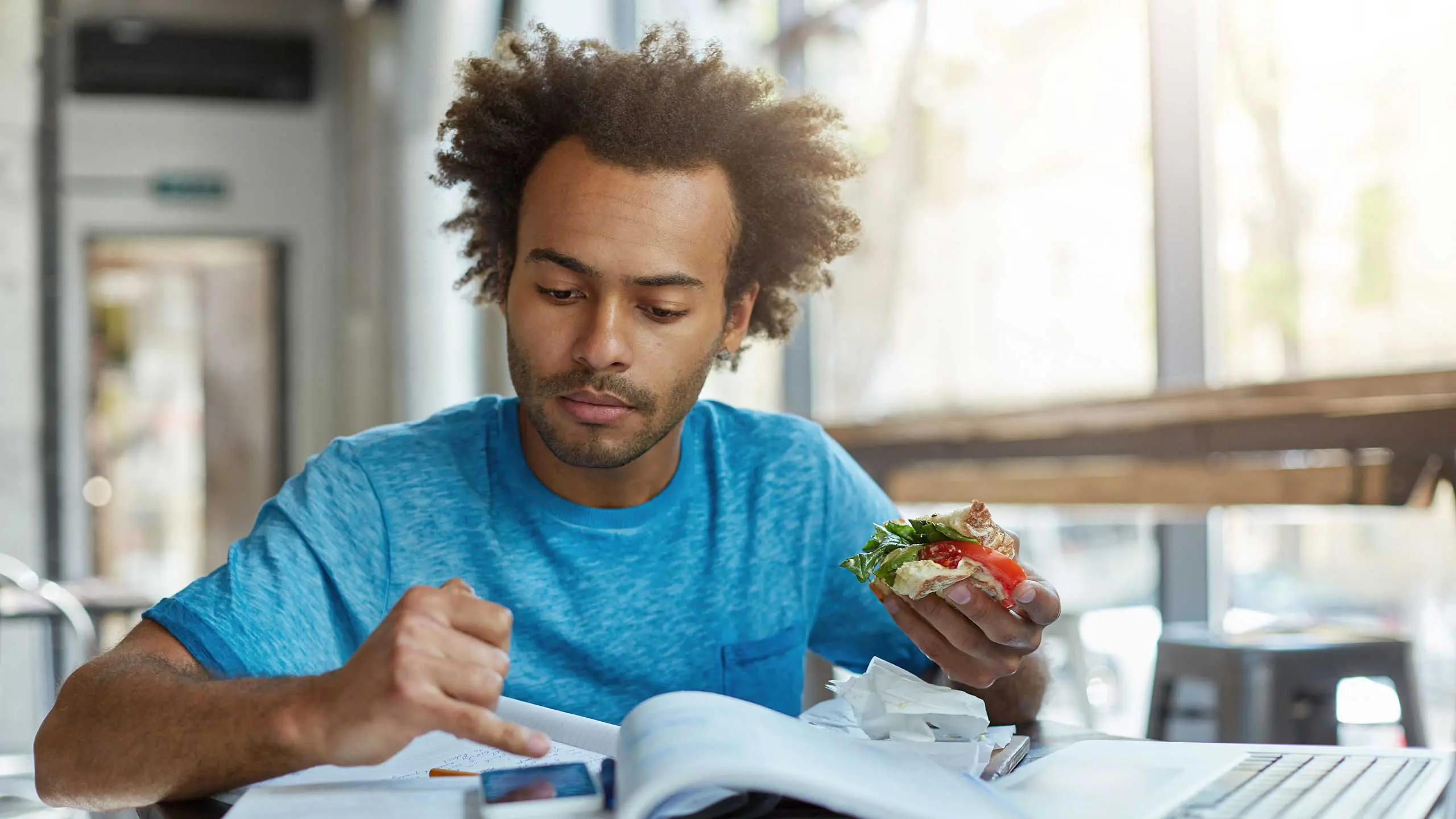 Student eating sandwich while studying